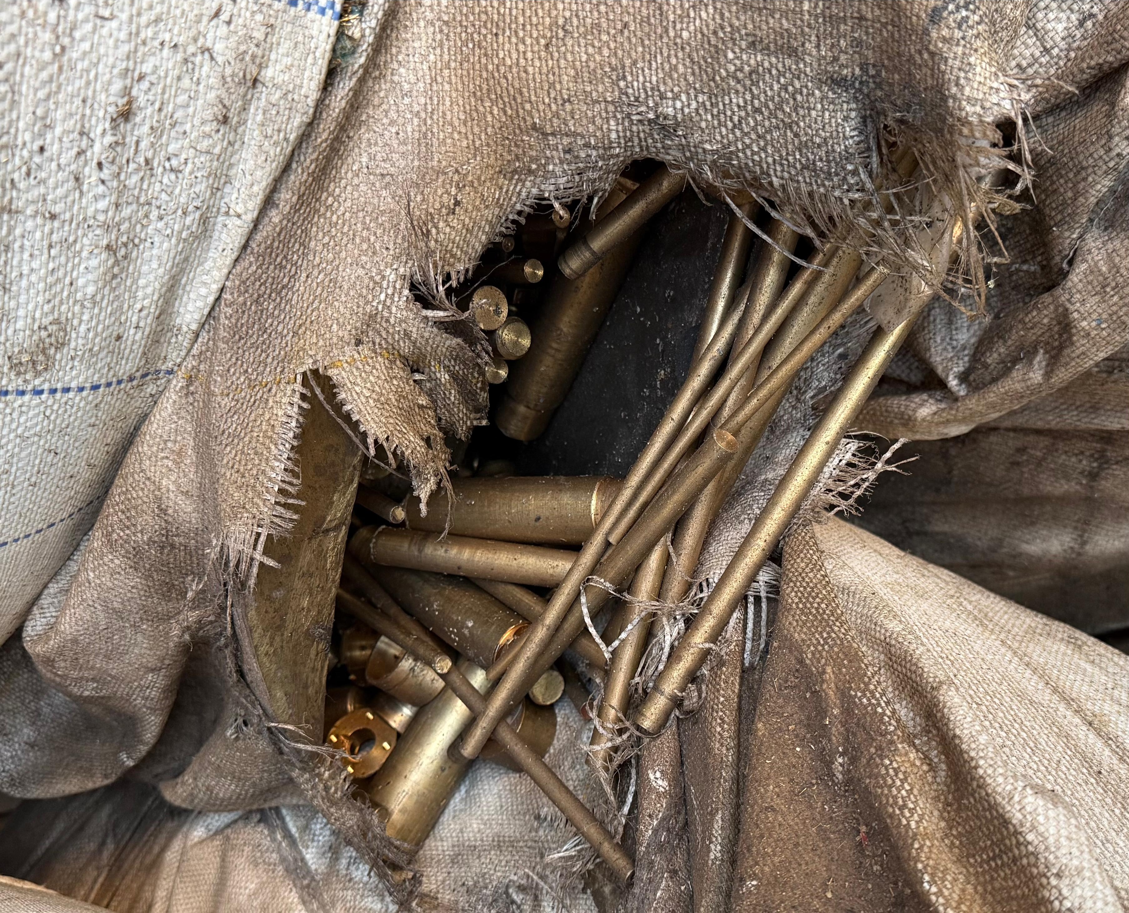 Brass scrap rods collected inside a large industrial recycling bag